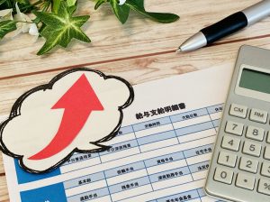 給与明細書と電卓、ペン、アップの矢印
