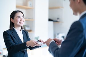 笑顔で名刺交換する営業ウーマン