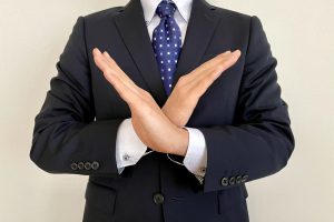 両手で×印を作るビジネスパーソン