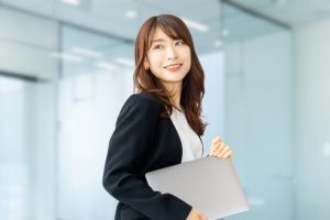 パソコンを手に笑顔で振り返るビジネスウーマン