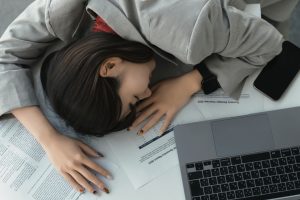 疲れて机に伏せる女性